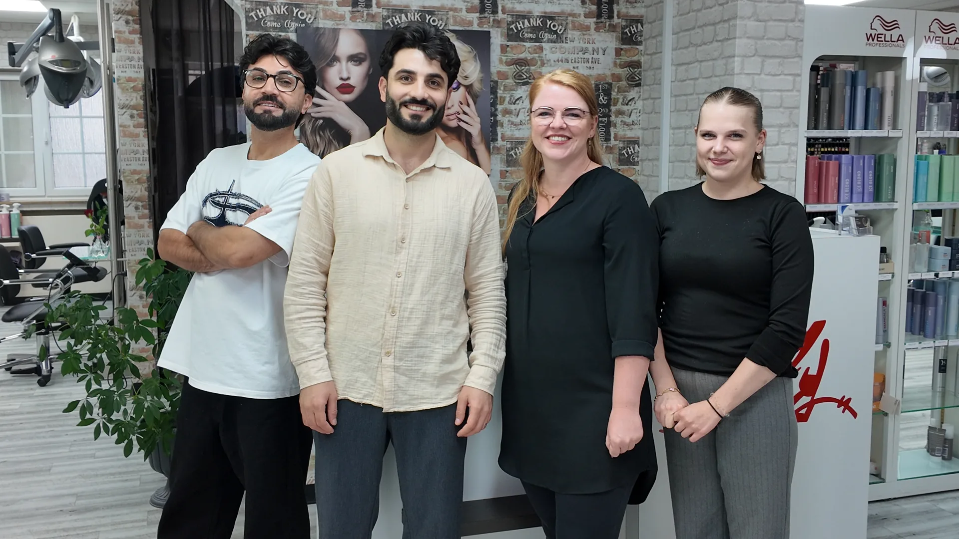 Das vierköpfige Team von Crazy Hair im Salon, vor der Ziegelwand und dem Wella-Regal